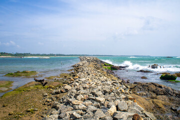 Beautiful tropical landscape. A stone ocean shore with waves and rocks. Beautiful texture background for tourism, design and advertising