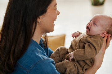 A young new mom holding in arms and looking at her cute newborn baby girl