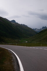 View on road in green mountains in cloudy weather in Alps
