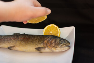 Whole salmon on a plate sprinkled with lemon juice