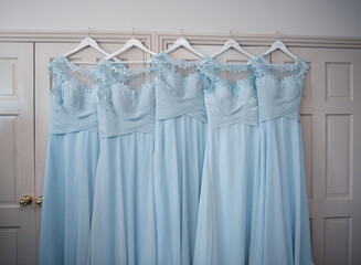 Five blue turquoise bridesmaid dresses hanging ready to wear at a wedding