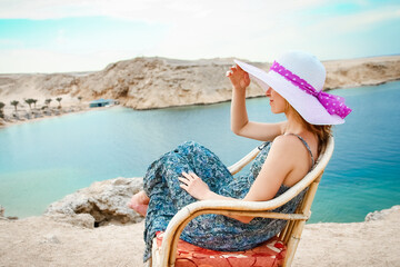 Stylish beautiful girl in hat on chair background