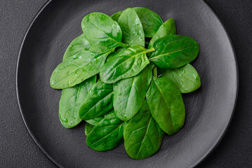 Fresh green spinach leaves on a black ceramic plate