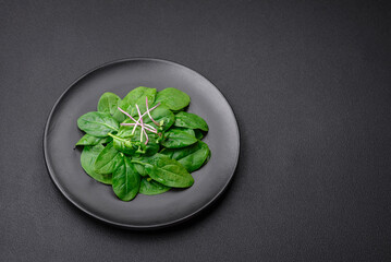 Fresh green spinach leaves on a black ceramic plate