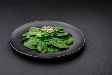 Fresh green spinach leaves on a black ceramic plate