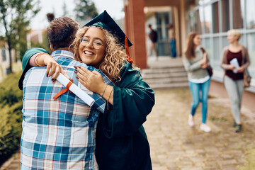 Happy graduate student embraces her father after graduation ceremony.