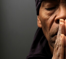 praying to god with hands together Caribbean man praying with black background stock photo