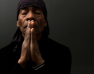 praying to god with hands together Caribbean man praying with black background stock photo