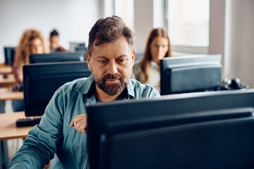 Mature man using desktop PC while attending computer class.