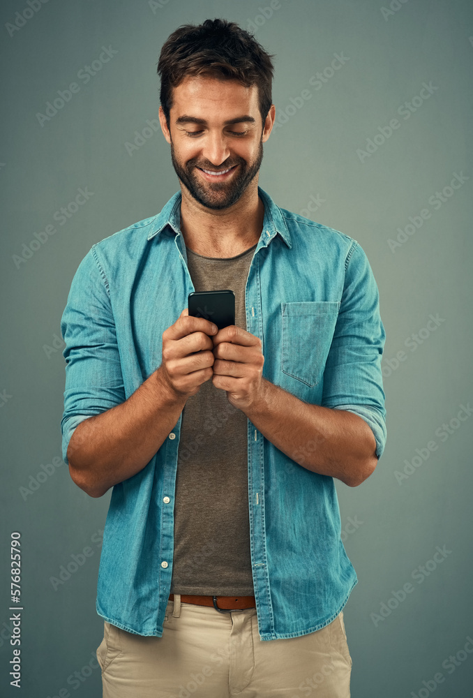 Poster hes the one everyone wants to be in contact with. studio shot of a handsome young man using a cellph