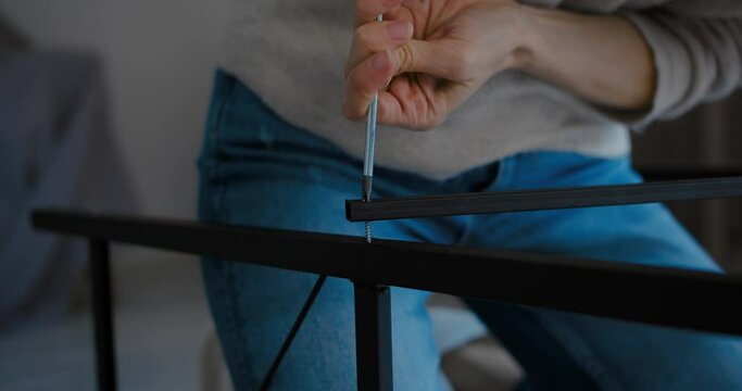 Young women working on DIY project putting together self-assembly furniture using hand screw