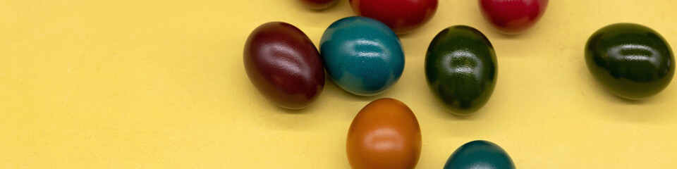 Banner 4x1. Colorful painted Easter eggs on a yellow textured background
