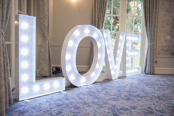 White light up Love sign at a wedding on the floor of a hotel or ceremony