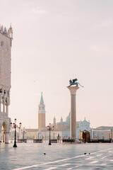 The famous lion in the square of San Marco in Venice. He watches over the city and shines in the sunshine allthough the sky is cloudy. The day is beautiful and warm!