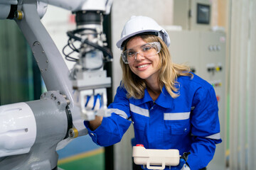 Professional engineer or technician worker hold controller and check or maintenance robotic arm machine in factory workplace also look at camera and smile.