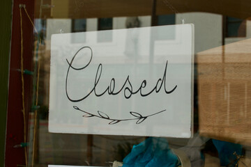 closed sign through the boutique shop window