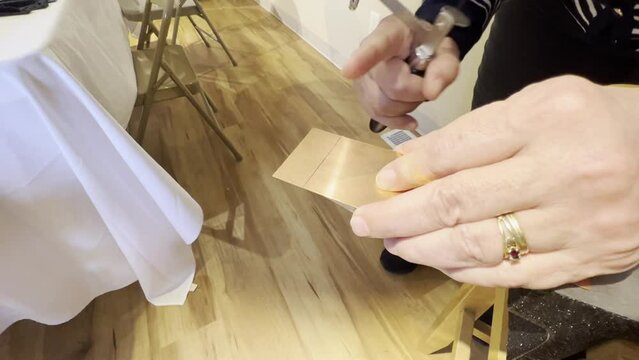 Closeup of woman's hands cutting metal with a jeweler's saw