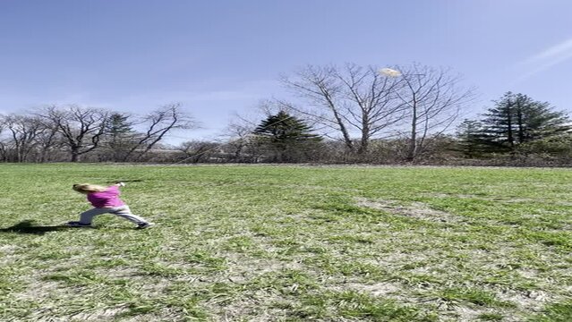 vertical video of a preschool girl in pink jacket flying a kite