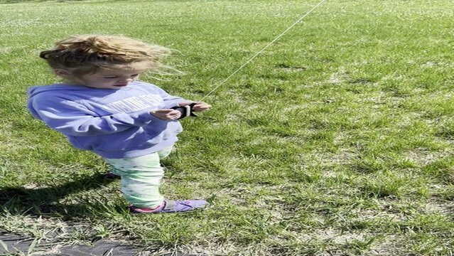vertical video of young girl in blue sweatshirt flying a kite