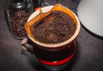 Brewing coffee in a funnel. The process of making branded coffee in a funnel on a gray wooden table. In the early morning, pour the coffee that blooms in the dropper.