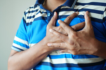 young man suffering pain in heart and holding chest with hand 