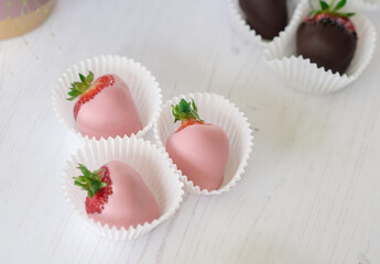 Pink chocolate covered or dipped strawberries in paper cases on a white background