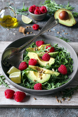 Avocado salad with arugula, raspberries and sunflower seeds. Top view. Healthy food.