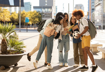 Fototapeta premium Young group of happy friends using mobile smart phones together outdoors. Multiracial teenagers having fun together sharing social media content on cell phone app. Technology lifestyle concept