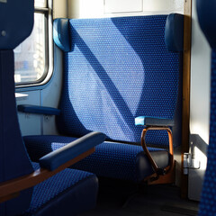 Public transport interior. We see a blue seat in a train car.