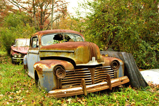 Old rusty American car in a scrap yard