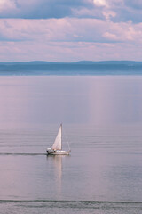 Sailboat on a sunny day with mountains in the back and a beautiful sky with nice clouds