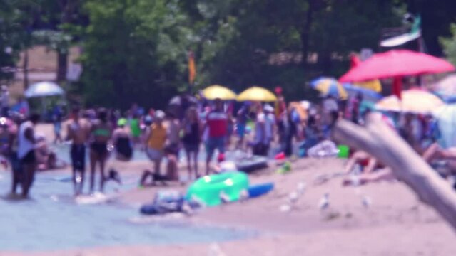 Lens effect heat wave. Blurry sandy beach with people on hot summer day. Blurred people at lake or sea and trees background. Holiday and tourist vacations sunbathing and relaxing at sunny day