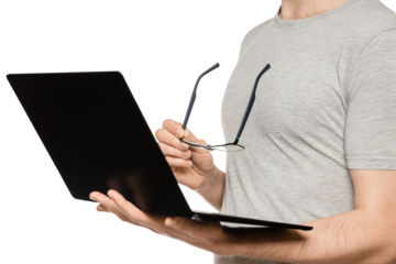 A man holds a laptop in one hand and glasses in the other. Slim ultrabook in matte black with a touch screen. The concept of fatigue from working at the computer.