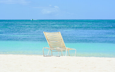 A white chair on the beach. Caribbean holiday vibes. Space for copy. 