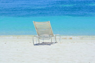 A white chair on the beach. Caribbean holiday vibes. Space for copy. 