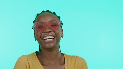 Face, fashion and sunglasses with a black woman in studio on a blue background to model eyewear. Portrait, smile and style with an attractive young female indoor to promote a designer brand of shades