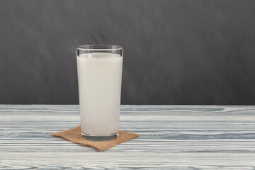 Tibicos or Water kefir in tall glass on grey  background. White muddy Fermented drink made with water and symbiotic culture of bacteria and yeasts. Healthy probiotic Tibi drink - obrazy, fototapety, plakaty