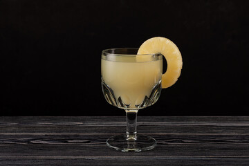 Delicious pineapple juice in drinking glass on dark wooden table. Selective focus, copy space
