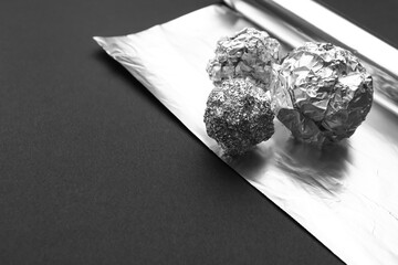 Crumpled balls of aluminium foil on dark background, closeup