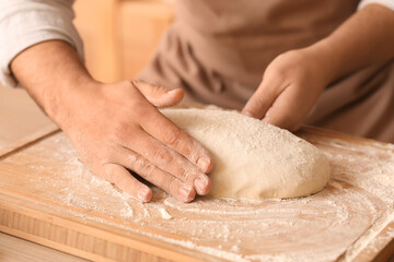 Fototapeta premium Male baker preparing dough for bread at table in kitchen, closeup
