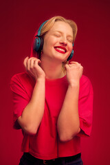 Fototapeta premium A happy young woman is dancing and enjoying music while standing isolated on magenta background. Viva magenta.