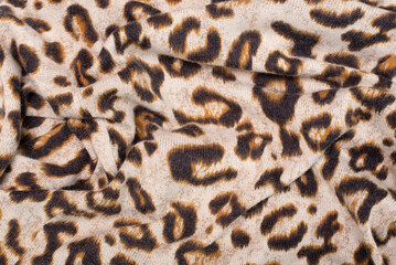 Wavy fabric with the image of the skin of a wild predator, leopard or cheetah, close-up