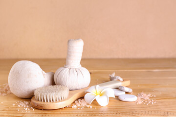 Fototapeta na wymiar Massage brush, herbal bags, spa stones and sea salt on wooden table