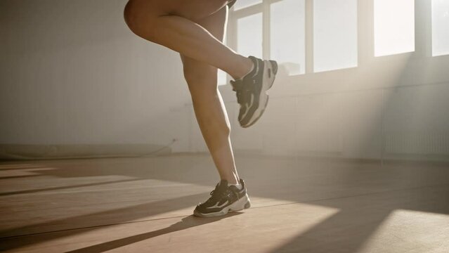 Close-up of legs of female athlete jumping with skipping rope in a smokey gym interior. Slow motion