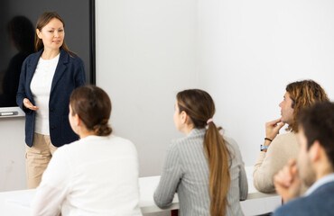 Experienced female teacher giving lecture to group of student
