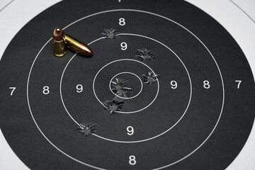Naklejka premium Target for shooting with bullet holes in the center and 9mm cartridges.