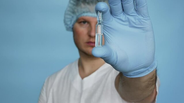 Doctor in a dressing gown demonstrates the medicine in a medical ampoule. Treatment liquid medicine in an ampoule. Male worker pharmacist