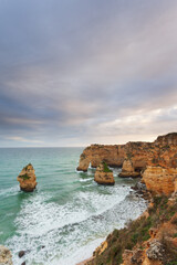 Fototapeta na wymiar Landscape on the Algarve coast at sunset. Beach in southern Portugal the best travel destination for tourists on vacation. seascape with caves through the cliffs