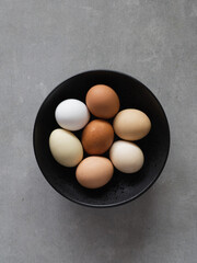 Minimalist Easter eggs. Nature colors eggs on a black plate on gray background. A chicken egg as a valuable nutritious product. Top view flat lay
