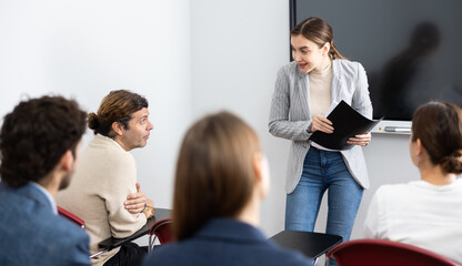 Young female teacher giving lecture to group of student